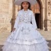 A girl wearing a traditional charro dress with silver embroidery with a sombrero in front of a colonial church