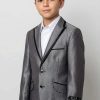 a boy wearing a shiny grey suit with matching pants and a white shirt.