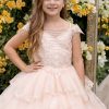 A girl wearing a pale blush multi layered dress with a white and yellow bugambilia background
