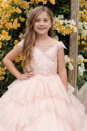 A girl wearing a pale blush multi layered dress with a white and yellow bugambilia background