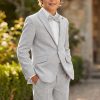 Boy wearing a light grey linen suit with white shirt and bow tie outdoors
