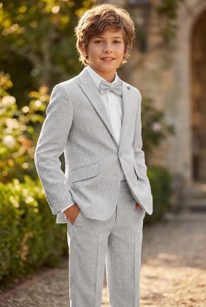 Boy wearing a light grey linen suit with white shirt and bow tie outdoors