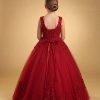 a girl wearing a deep burgundy color ball-gown in a gold background