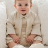 a baby boy sitting with a baptism gown