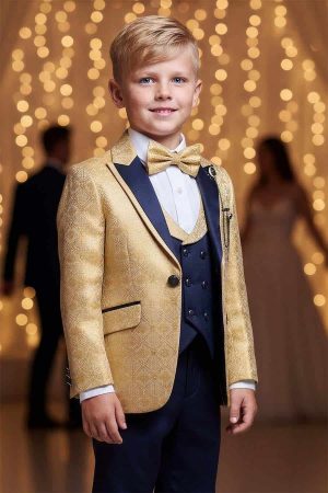 Boys gold jacquard tuxedo with navy blue satin lapel, matching vest, trousers, white dress shirt, and gold bow tie.