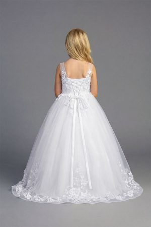 Young girl wearing a white sleeveless formal dress with floral appliqué bodice and full tulle skirt on a neutral background.