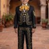Boy wearing a black and gold charro mariachi suit with gold embroidered horseshoes and horse heads, gold metal buttons, matching sombrero, vest, white shirt, and bow tie.