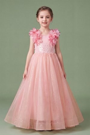 A girl wearing a blush dress with feathered shoulders and floor length. in a light sage color background